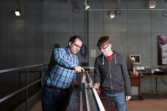 Dieses Bild zeigt zwei männliche Studierende in einem Labor für elektrische Maschinen.